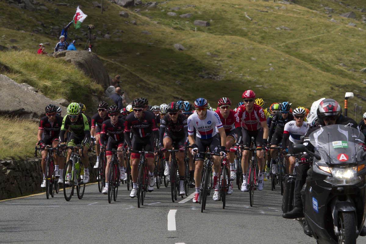 Tour of Britain 2015 - The peloton climbs Pen-y-Pass with fans waving a Welsh flag in the background