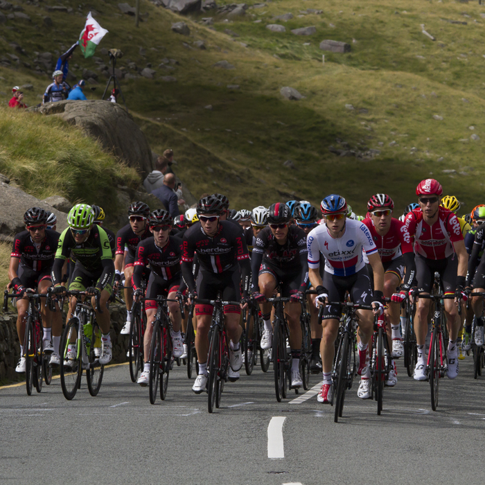 Tour of Britain 2015 - The peloton climbs Pen-y-Pass with fans waving a Welsh flag in the background