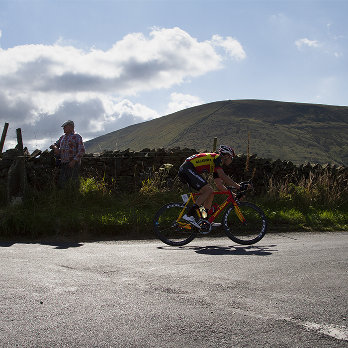 Tour of Britain 2015 - A rider passes an old man wearing a flat cap at the side of the road with the dominant feature of Pendle Hill in the background