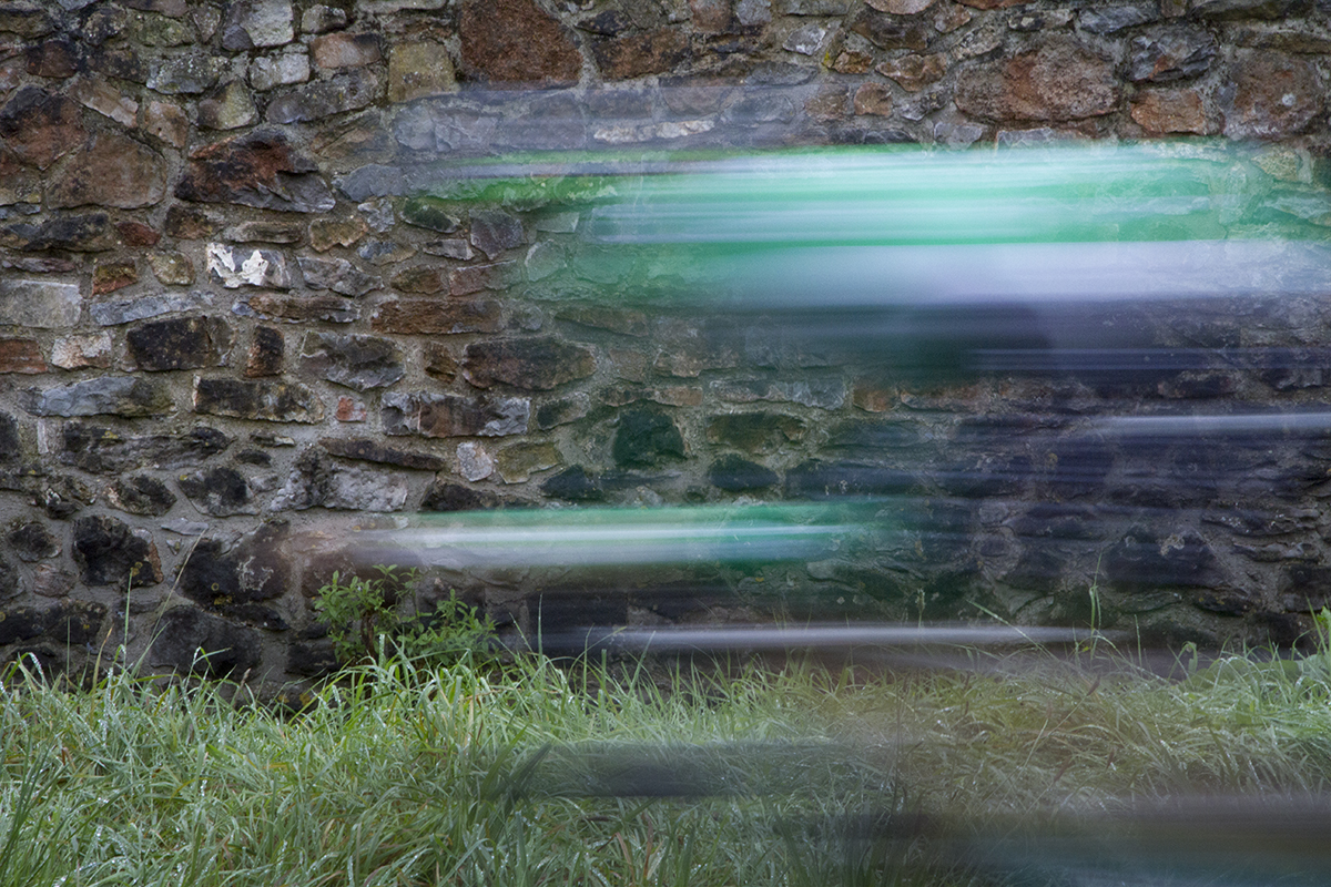 Tour of Britain 2016 - Motion blurred rider passes a stone wall competing in the time trial in Bristol