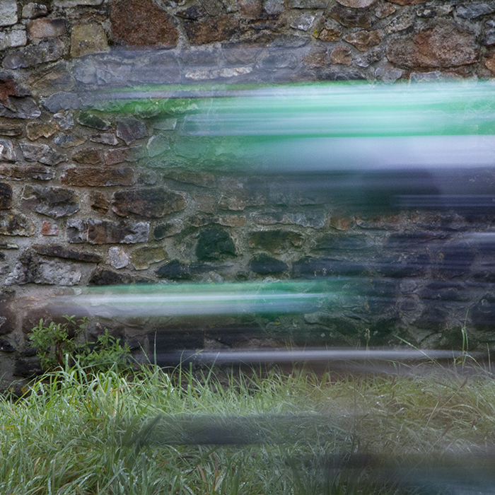 Tour of Britain 2016 - Motion blurred rider passes a stone wall competing in the time trial in Bristol