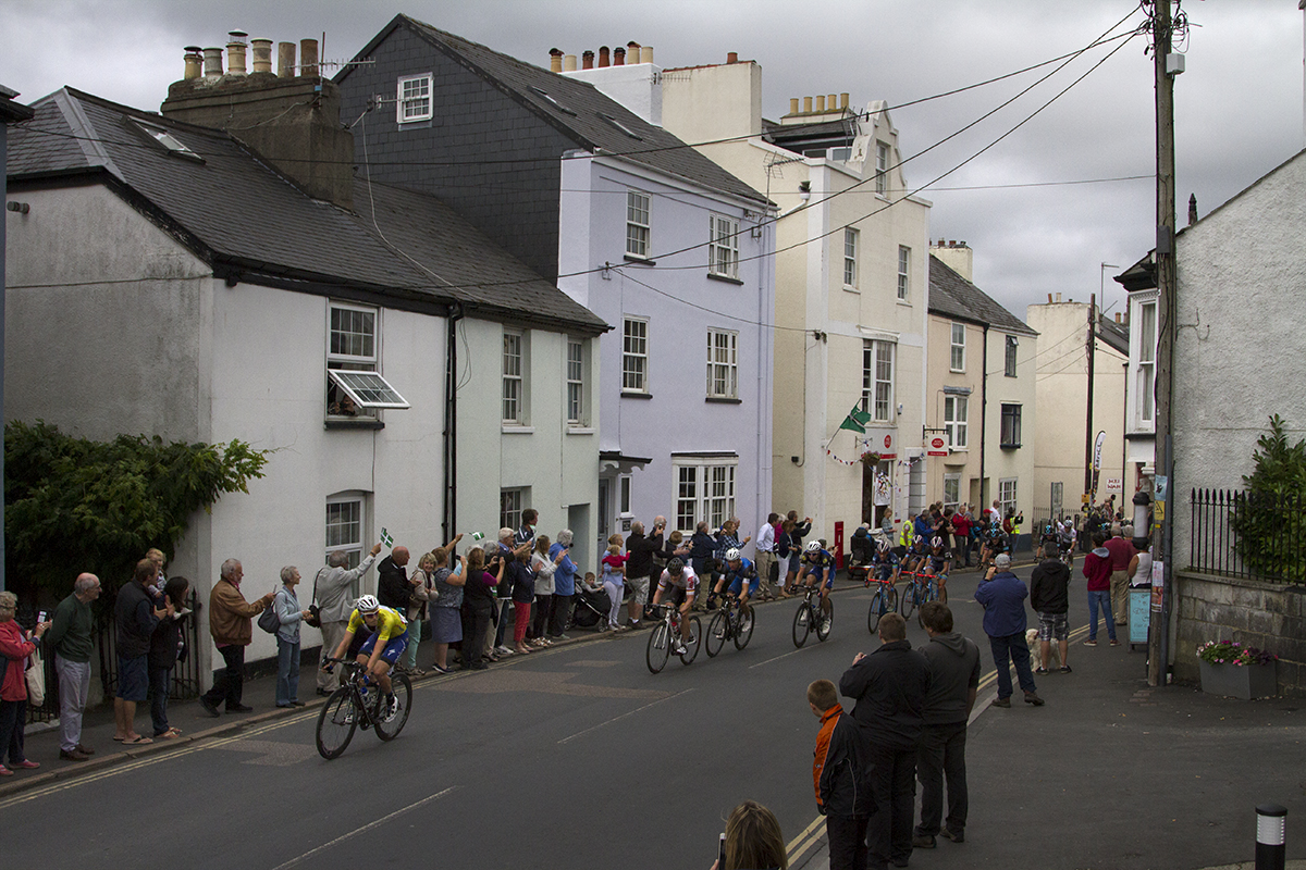 Tour of Britain 2016 - a group of riders pass cottages painted in pastel colours in Chudleigh