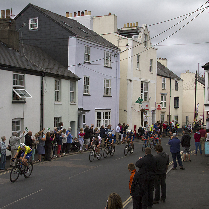 Tour of Britain 2016 - a group of riders pass cottages painted in pastel colours in Chudleigh