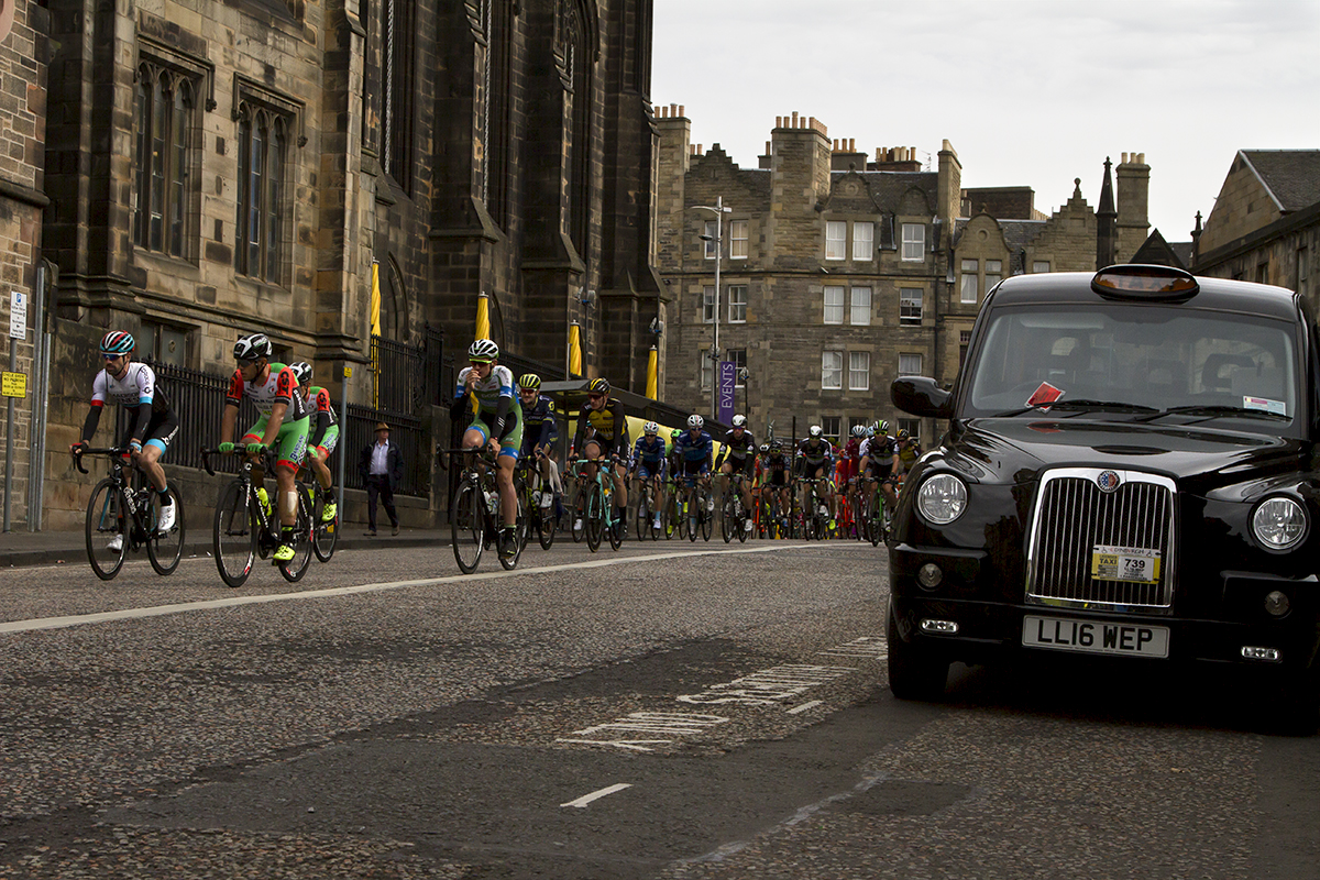 Tour of Britain 2017 - Riders pass by a black cab on their way through Edinburgh Old Town