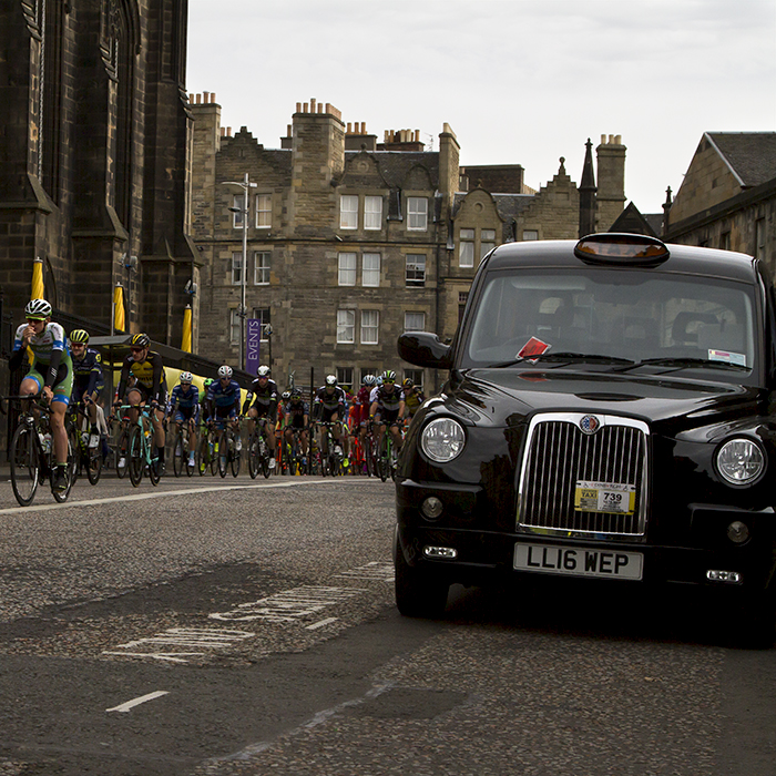 Tour of Britain 2017 - Riders pass by a black cab on their way through Edinburgh Old Town