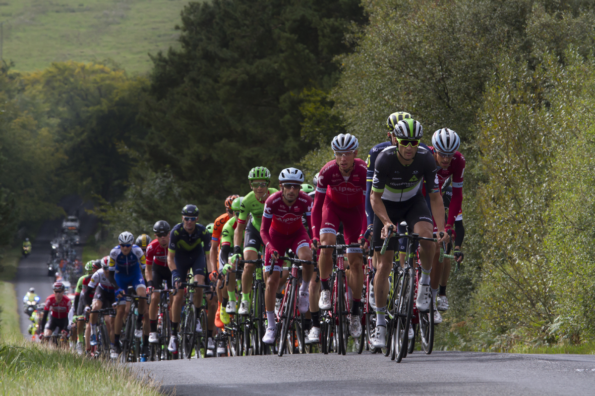 Tour of Britain 2017 - The peloton climbs a hill in the countryside near Rothbury