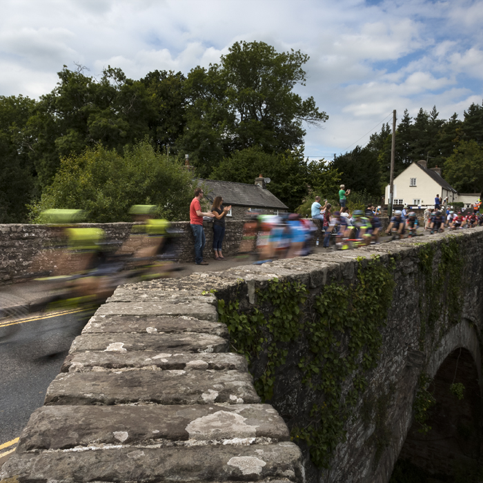 Tour of Britain 2018 - The peloton speeds over the bridge at Groesffordd