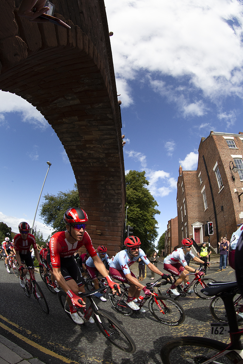 Tour of Britain 2019 - The peloton round the corner having passed under the walls at Chester