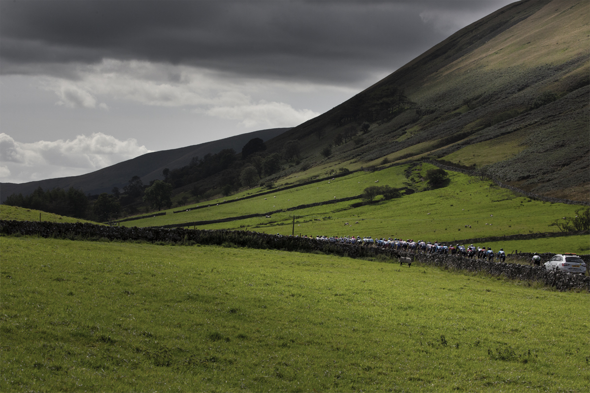 Tour of Britain 2019 - the peloton pass by dry stone walls in the hilly landscape near Sedburgh, Cumbria