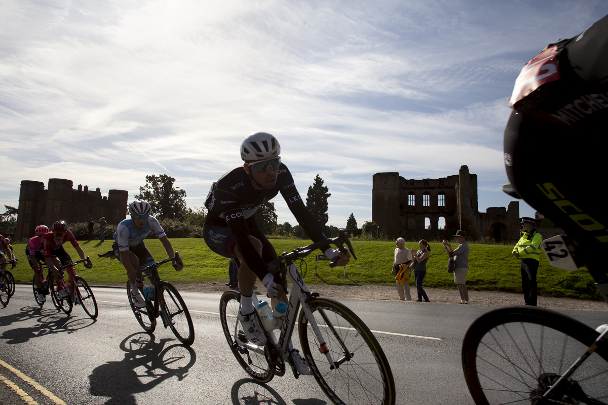 Tour of Britain 2019 - Silhouetted riders pass by Kenilworth Castle as spectators look on