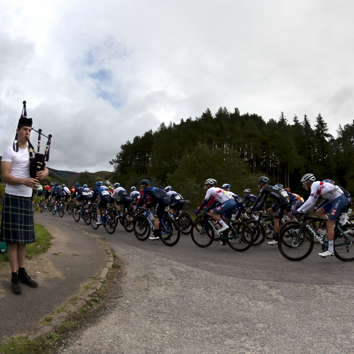 Tour of Britain 2021 - A bagpipe player serenades the peloton as it passes over Clattering Bridge in Scotland