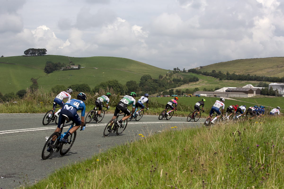 Tour of Britain 2021 - The peloton from behind round a corner in The Peak District