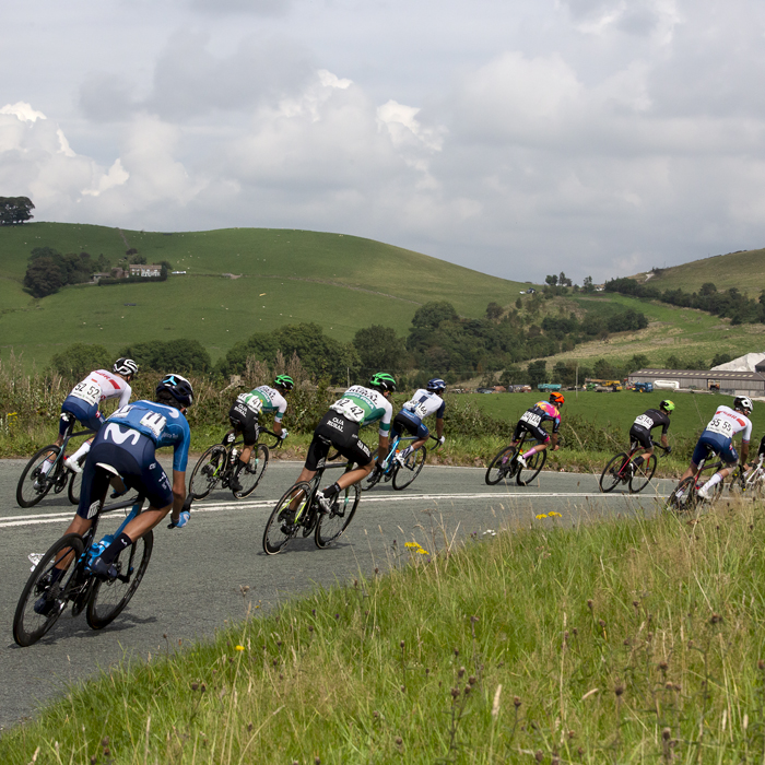 Tour of Britain 2021 - The peloton from behind round a corner in The Peak District