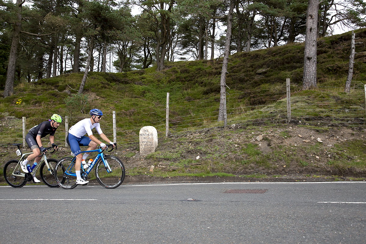 Tour of Britain 2021 - Two riders pass near a milestone on the Nenthead climb