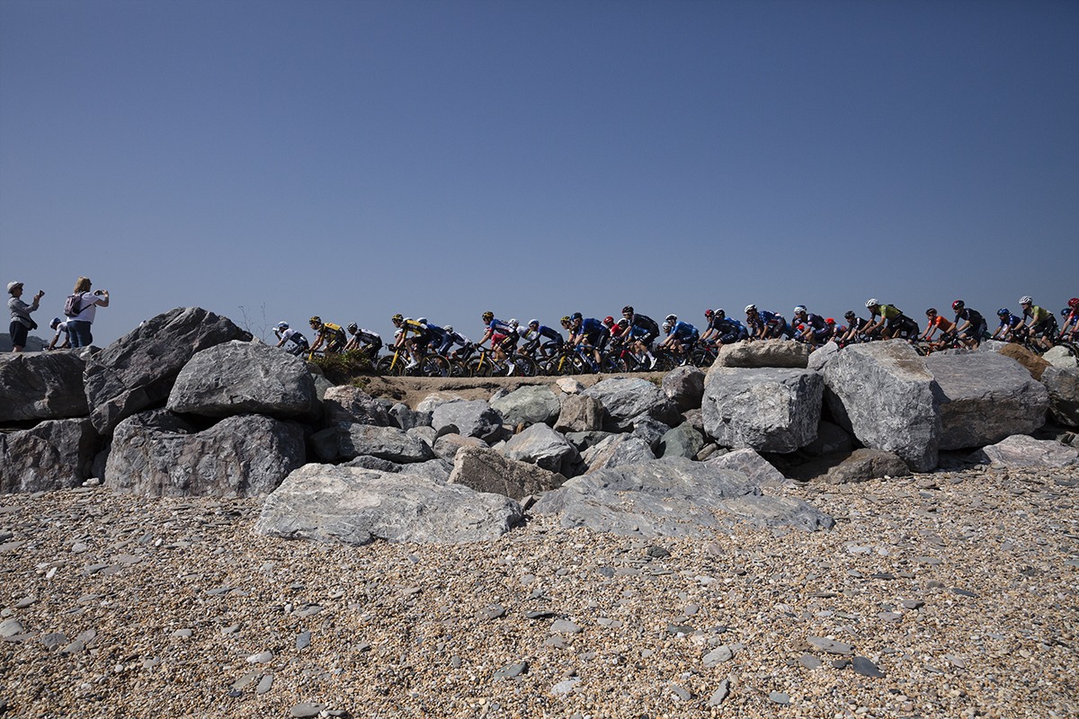 Tour of Britain 2021 - Side view of the peloton taken from the pebble beach on Slapton Ley