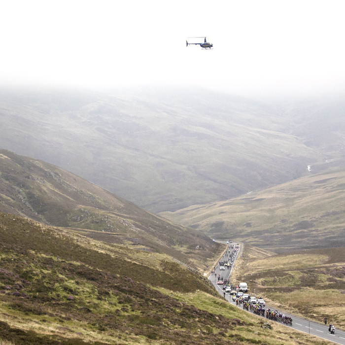 Tour of Britain 2022 -  Low cloud shrouds Cairnwell Pass as the peloton approach in the distance. 