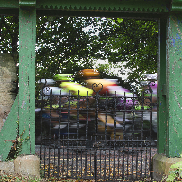 Tour of Britain 2022 - The race with motion blur framed by a green gate