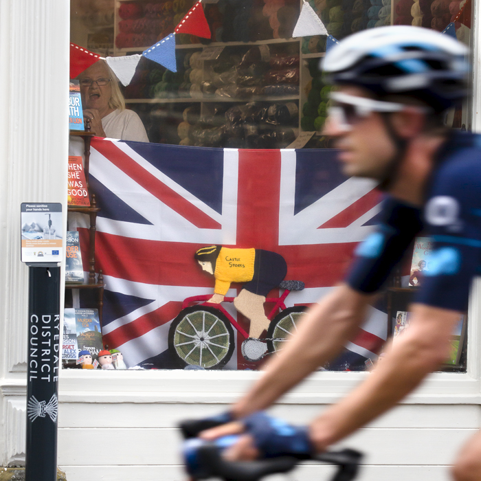 Tour of Britain 2022 - A lady in a wool shop at the side of the race gasps as she sees the riders pass