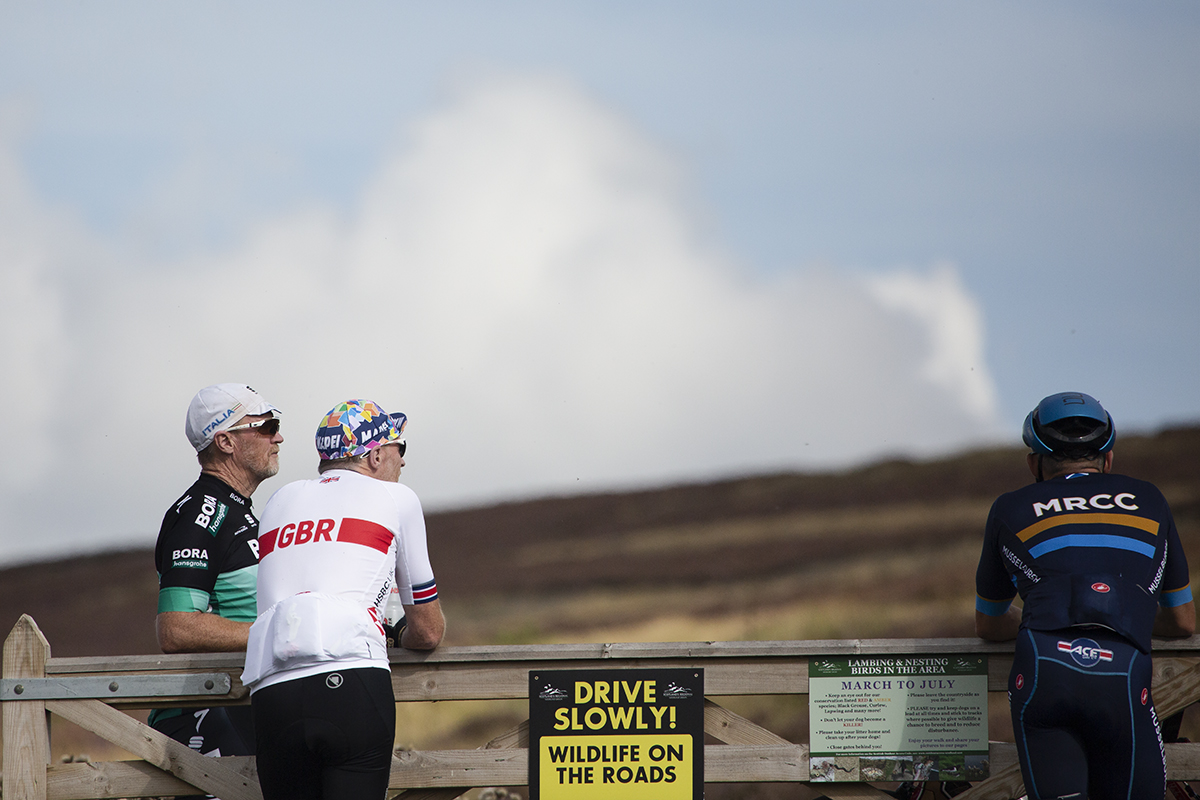 Tour of Britain 2022 - Fans dressed in cycling gear lean on gate waiting for the race to pass