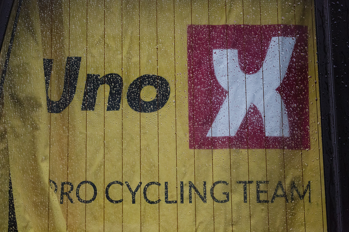 Tour of Britain 2022 -Uno-X Pro Cycling Team bus with the curtain bearing their name viewed through a wet window