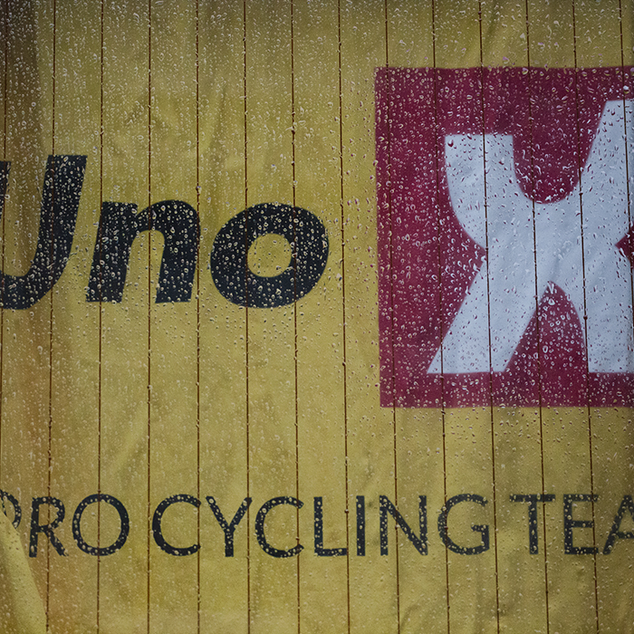 Tour of Britain 2022 -Uno-X Pro Cycling Team bus with the curtain bearing their name viewed through a wet window