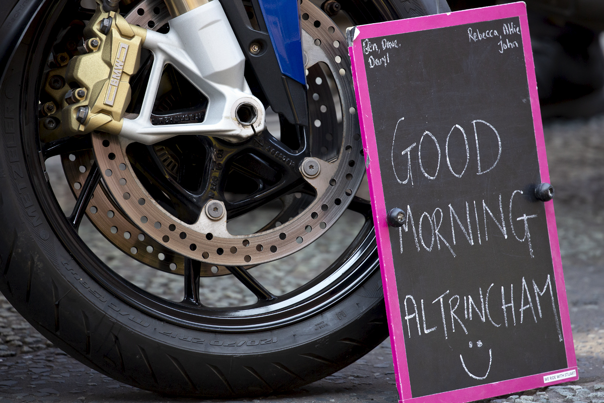 Tour of Britain 2023 - Good Morning Altrincham written on a chalk board propped up against a motorbike wheel