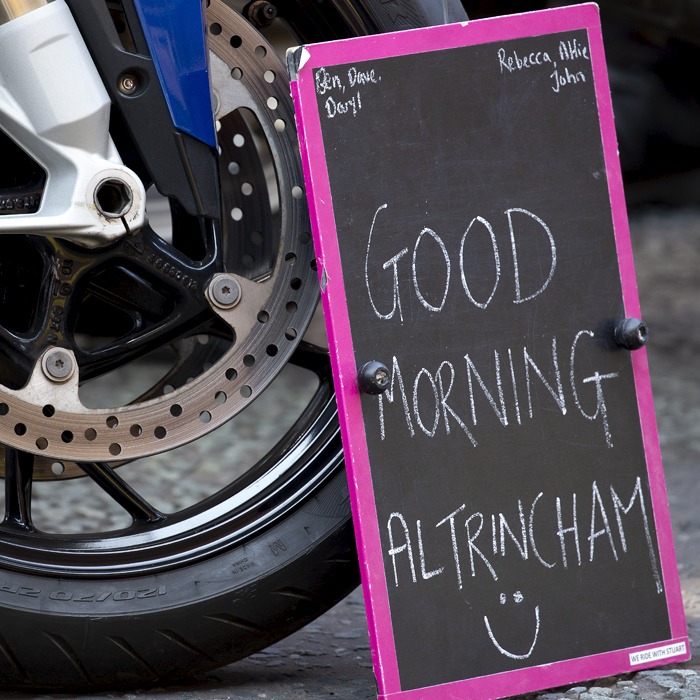 Tour of Britain 2023 - Good Morning Altrincham written on a chalk board propped up against a motorbike wheel