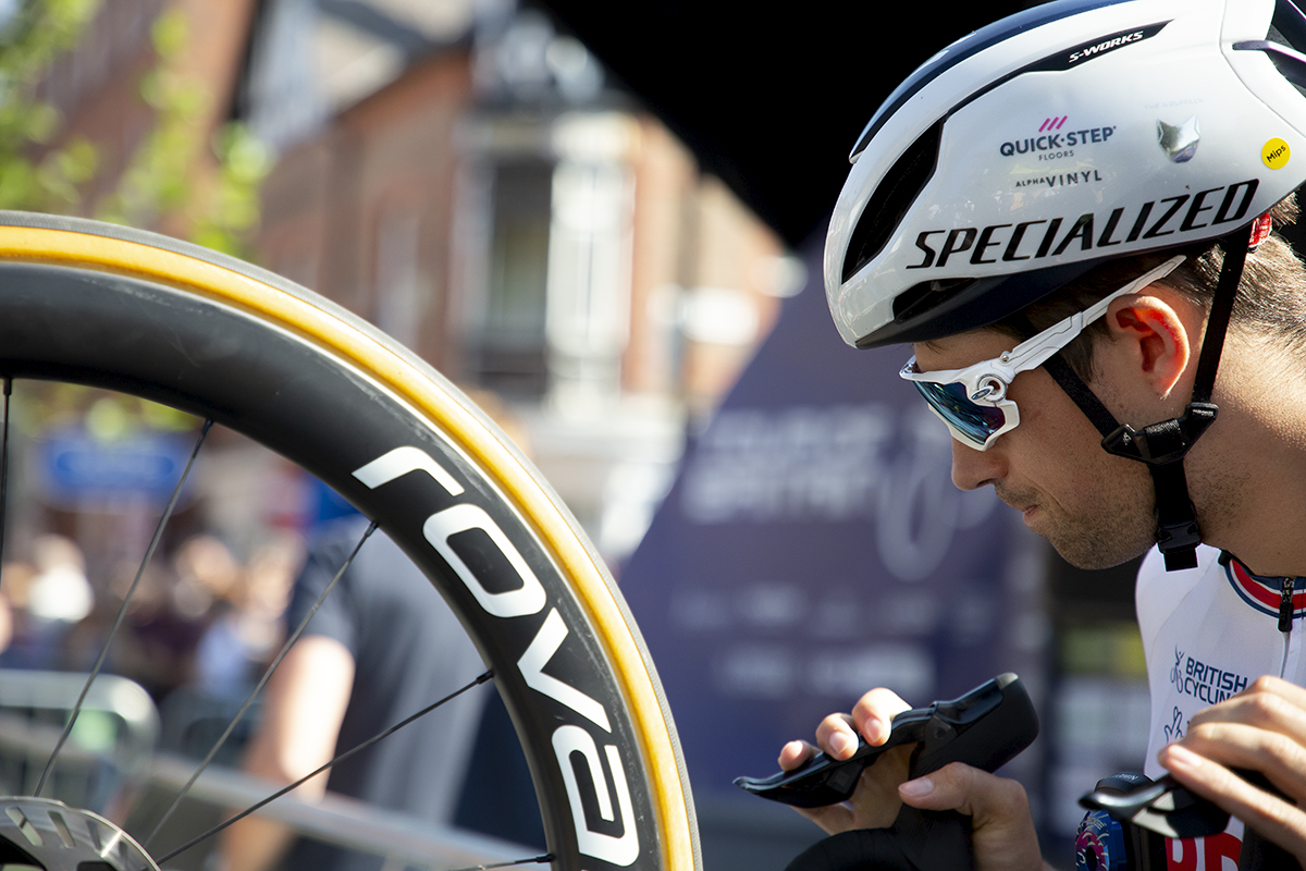 Tour of Britain 2023 - Ethan Vernon riding for Team GB wheels his bike on its rear wheel on the way to sign on