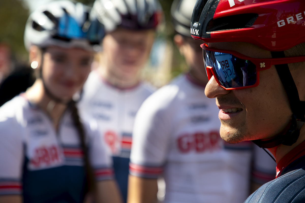 Tour of Britain 2023 - Tom Pidcock of INEOS Grenadiers looks to the side and smiles with young GB riders in the background