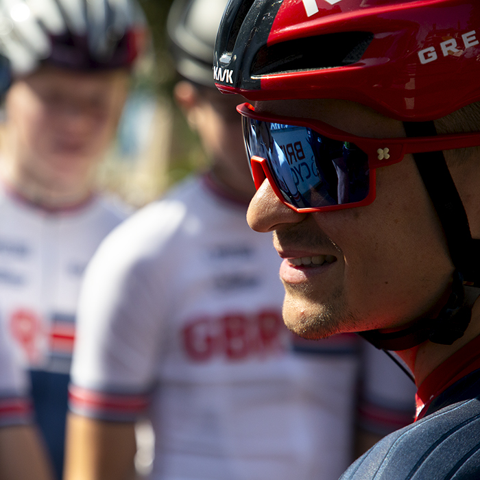 Tour of Britain 2023 - Tom Pidcock of INEOS Grenadiers looks to the side and smiles with young GB riders in the background