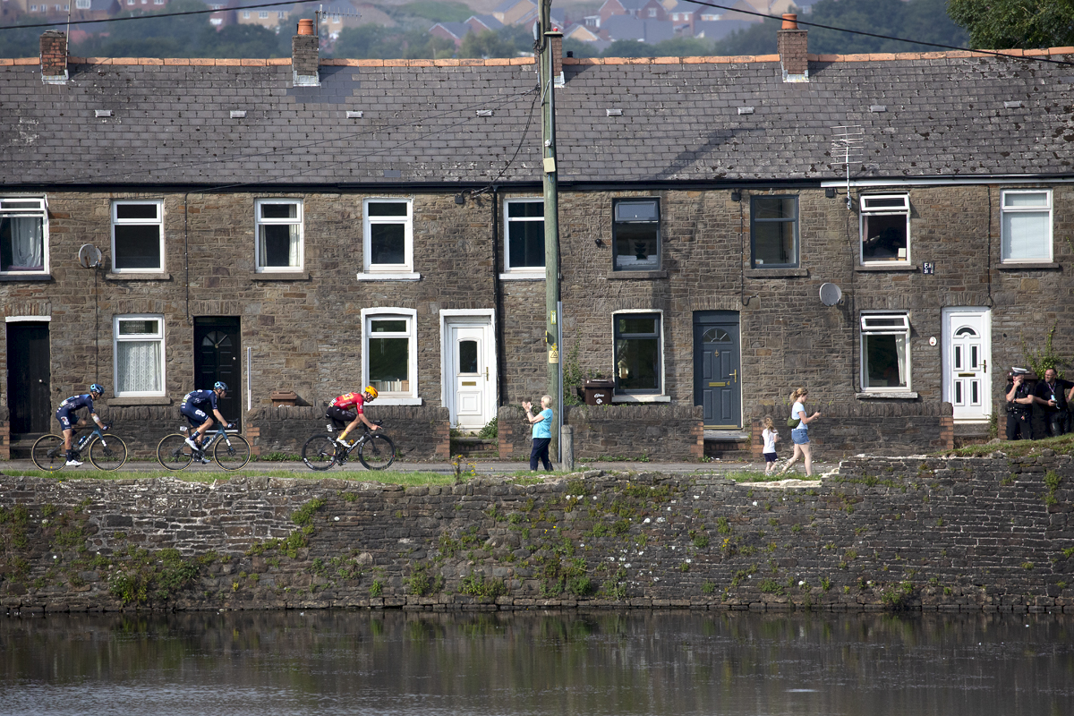 Tour of Britain 2023 - Riders pass a row of houses as spectators look on