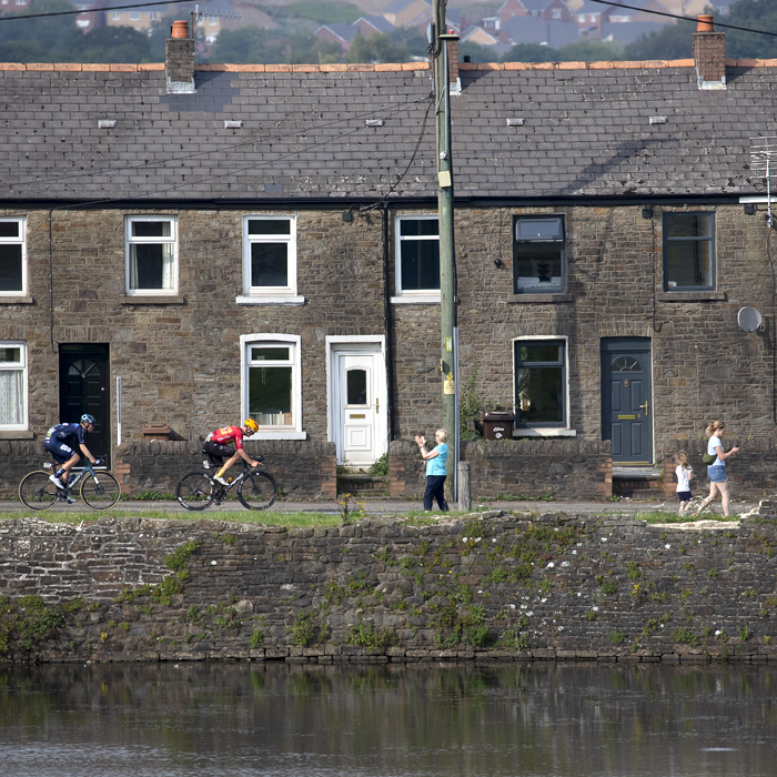 Tour of Britain 2023 - Riders pass a row of houses as spectators look on