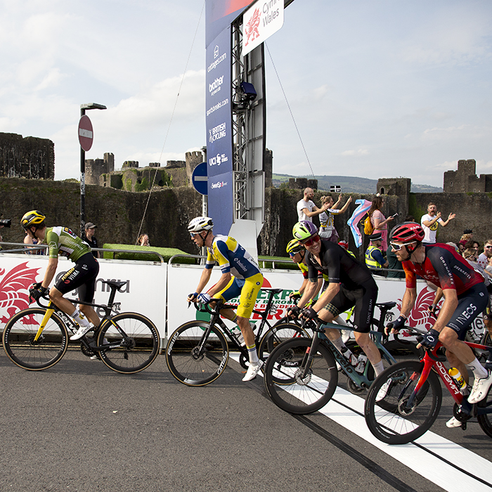 Tour of Britain 2023 - A group of riders cross the finish line for the first time with the castle in the background