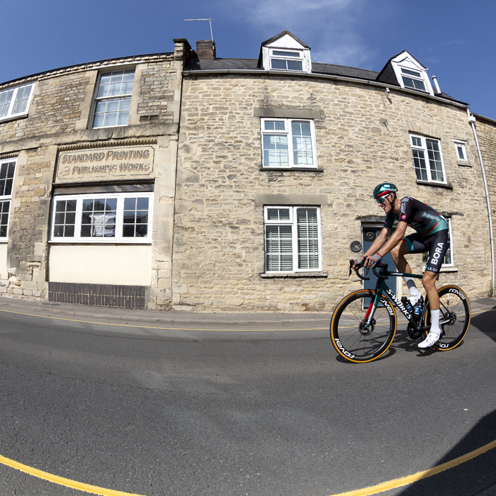 Tour of Britain 2023 - Nils Politt of BORA - hansgrohe passes sandstone buildings in the streets of Cirencester