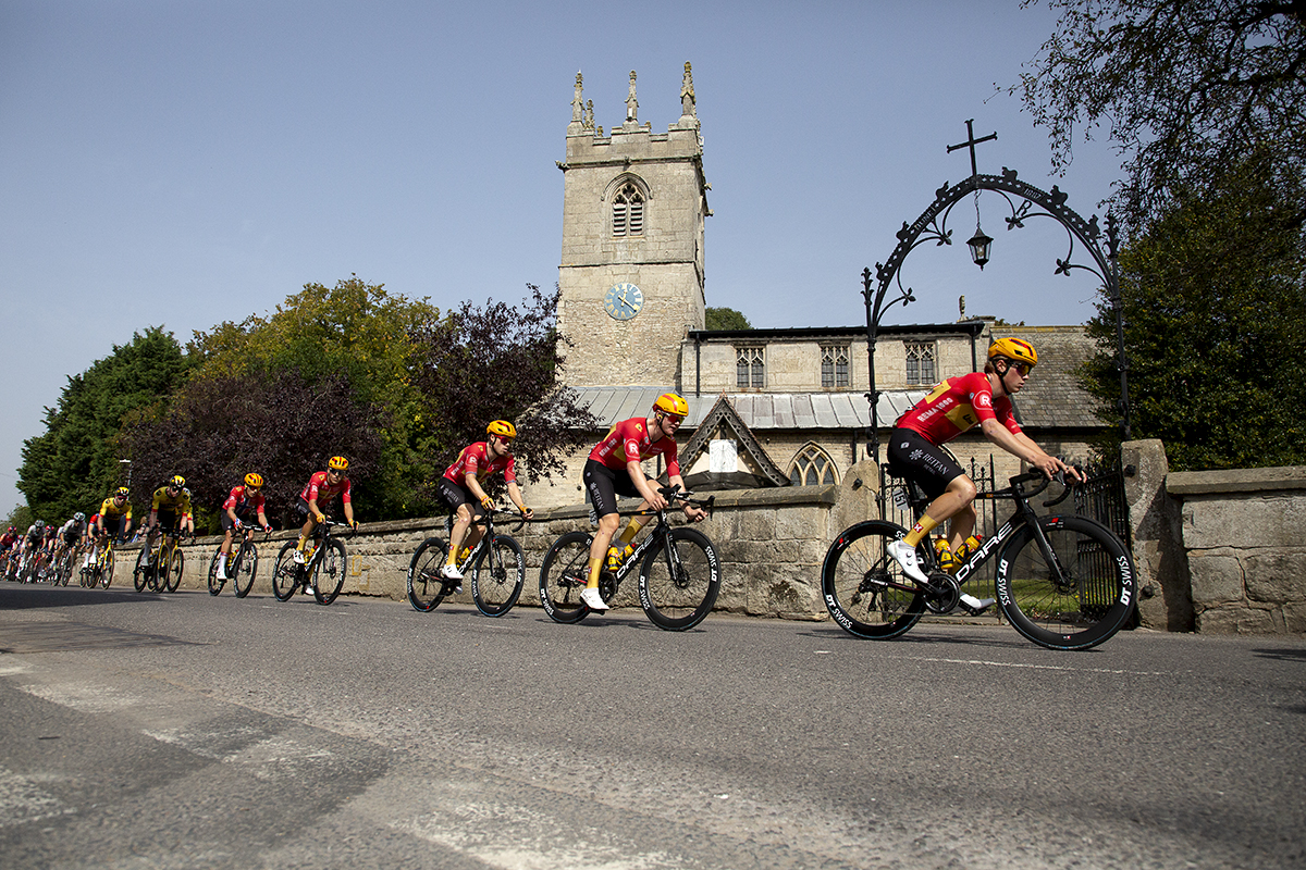 Tour of Britain 2023 - Uno-X Pro Cycling Team lead the riders past the church in Clayworth