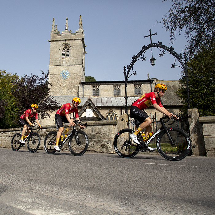 Tour of Britain 2023 - Uno-X Pro Cycling Team lead the riders past the church in Clayworth