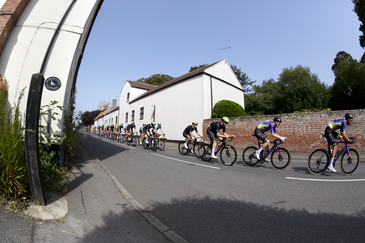 Tour of Britain 2023 - Riders pass traditional English buildings in Clayworth