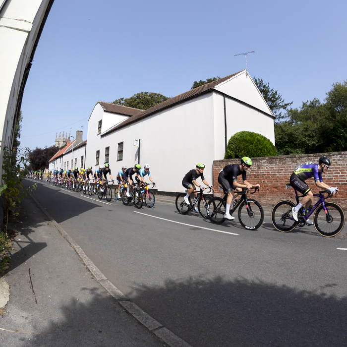 Tour of Britain 2023 - Riders pass traditional English buildings in Clayworth