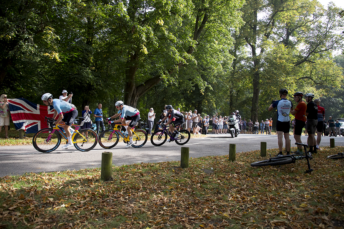 Tour of Britain 2023 - The breakaway passes fans holding a Union Jack in Clumber Park