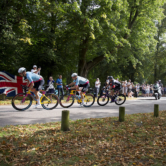 Tour of Britain 2023 - The breakaway passes fans holding a Union Jack in Clumber Park