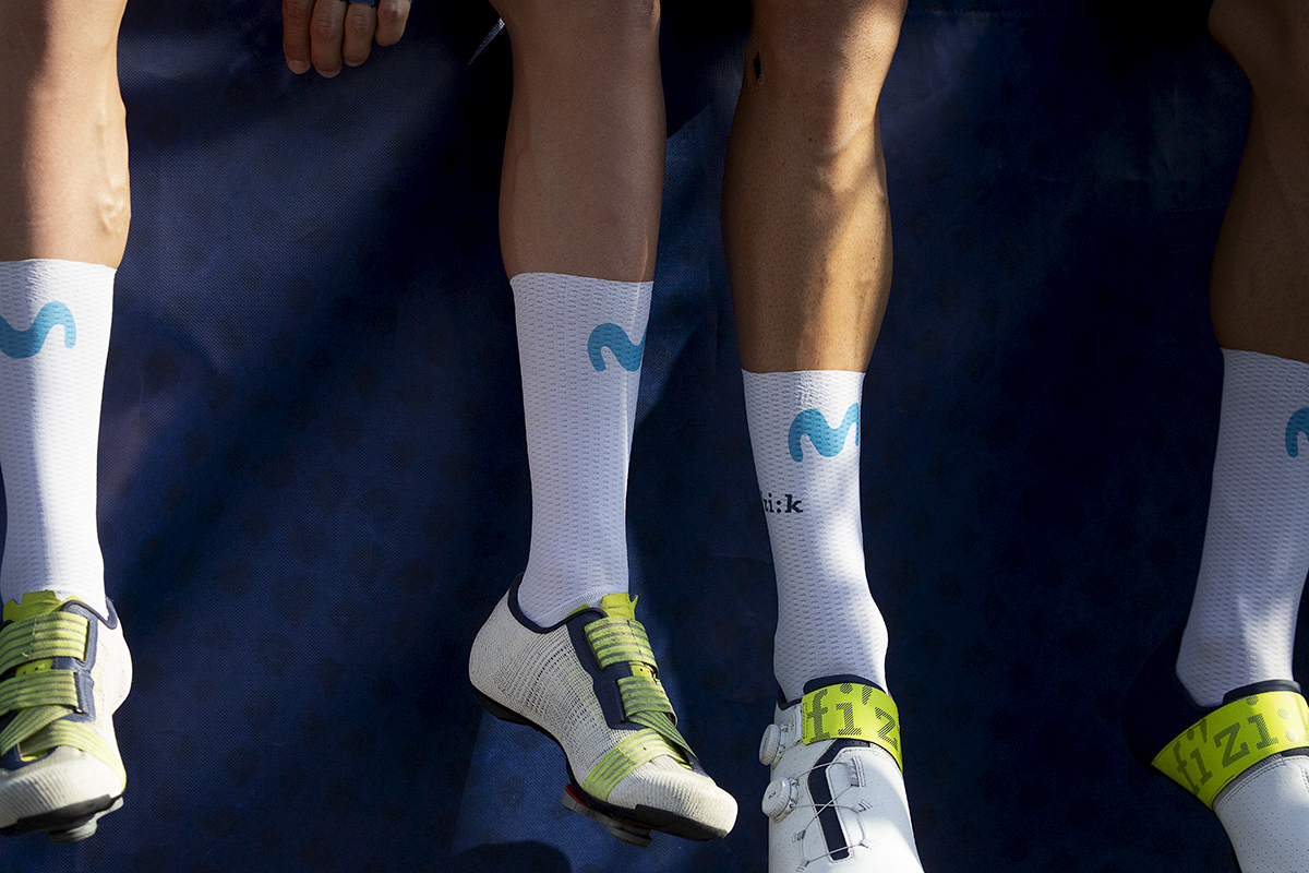 Tour of Britain 2023 - The legs of two Movistar Team riders as they dangle them from the edge of the podium