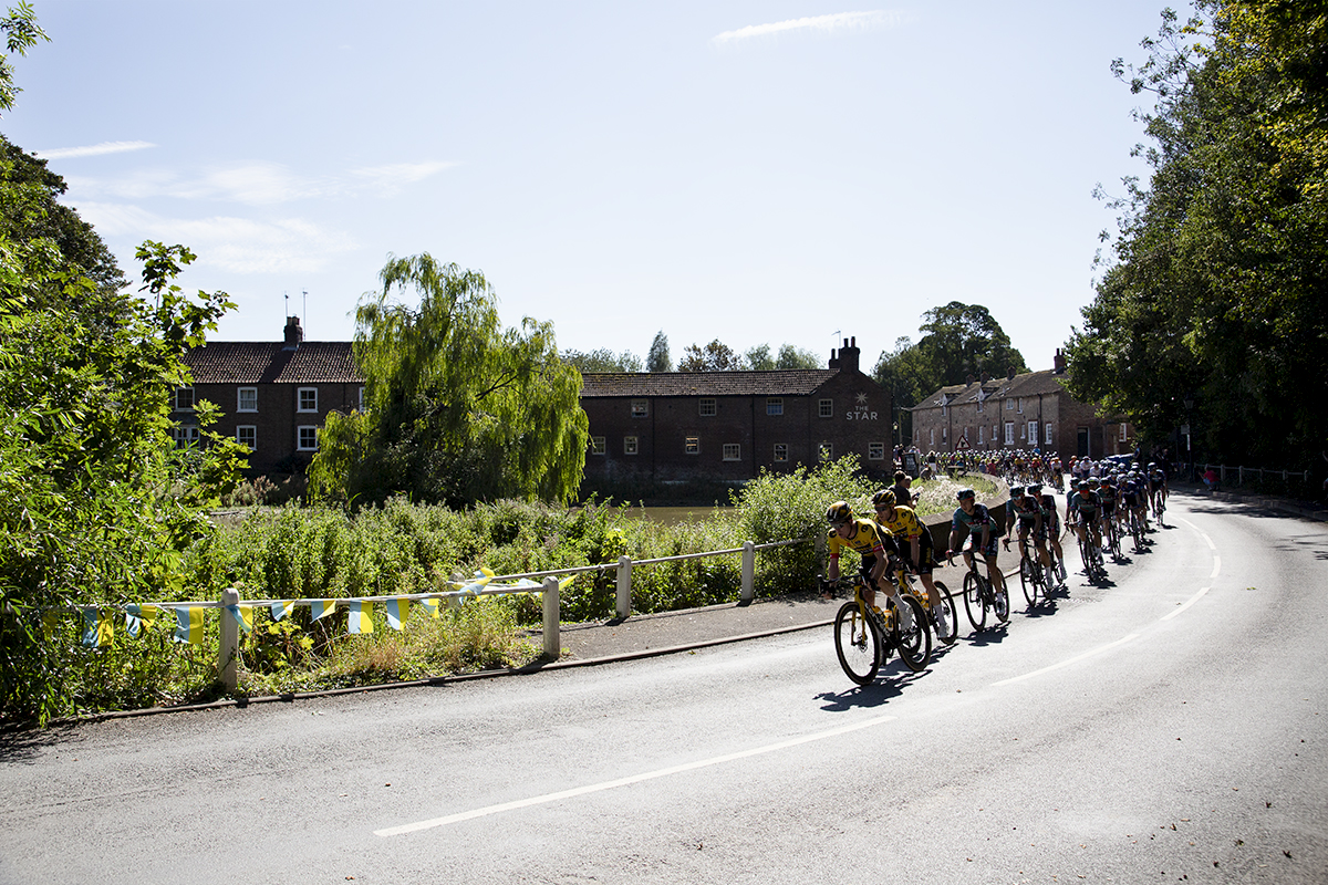 Tour of Britain 2023 - The peloton passes a village pond on its way through North Dalton