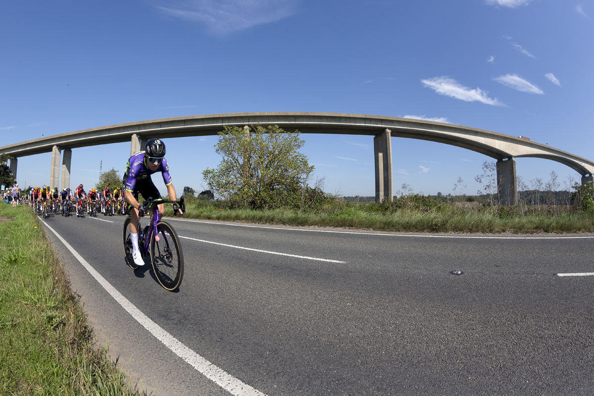 Tour of Britain 2023 - Ryan Christensen of Bolton Equities Black Spoke rides next to the River Orwell with the Orwell Bridge in the background