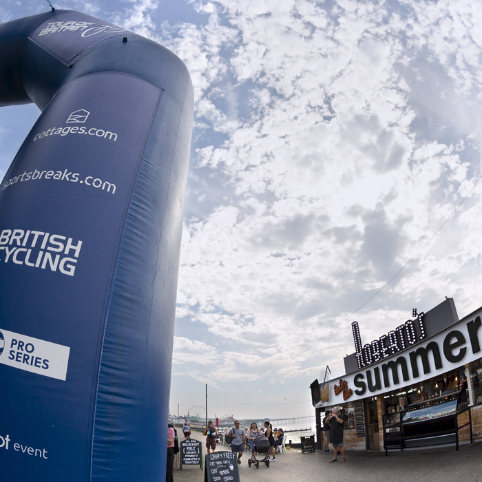 Tour of Britain 2023 - The start gate for the race near an ice cream stand with the pier in the background