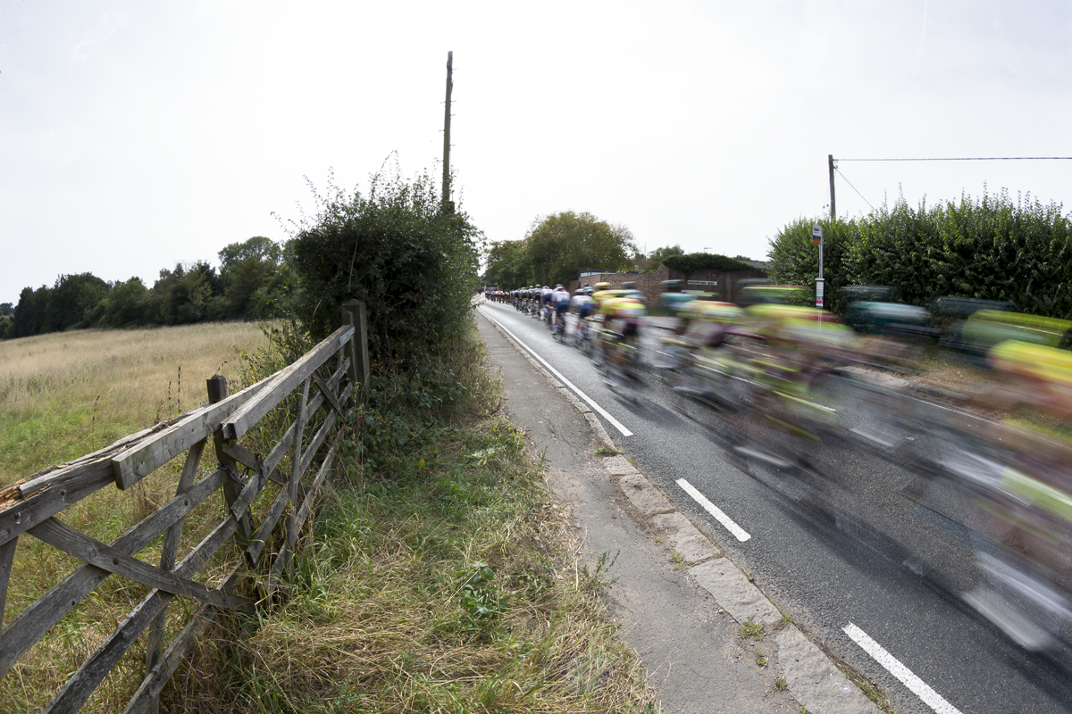 Tour of Britain 2023 - The race speeds past an old wooden five bar gate