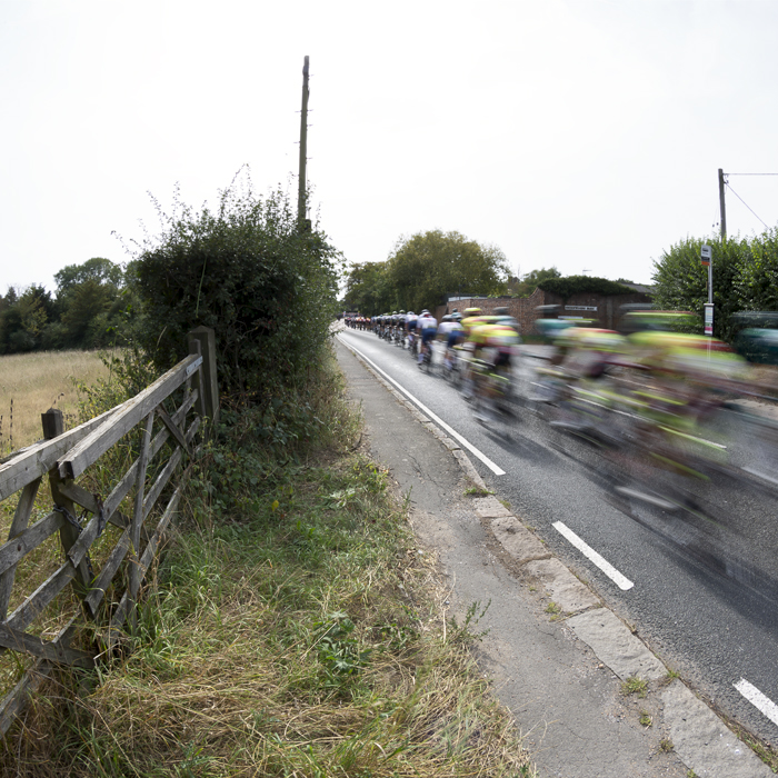 Tour of Britain 2023 - The race speeds past an old wooden five bar gate