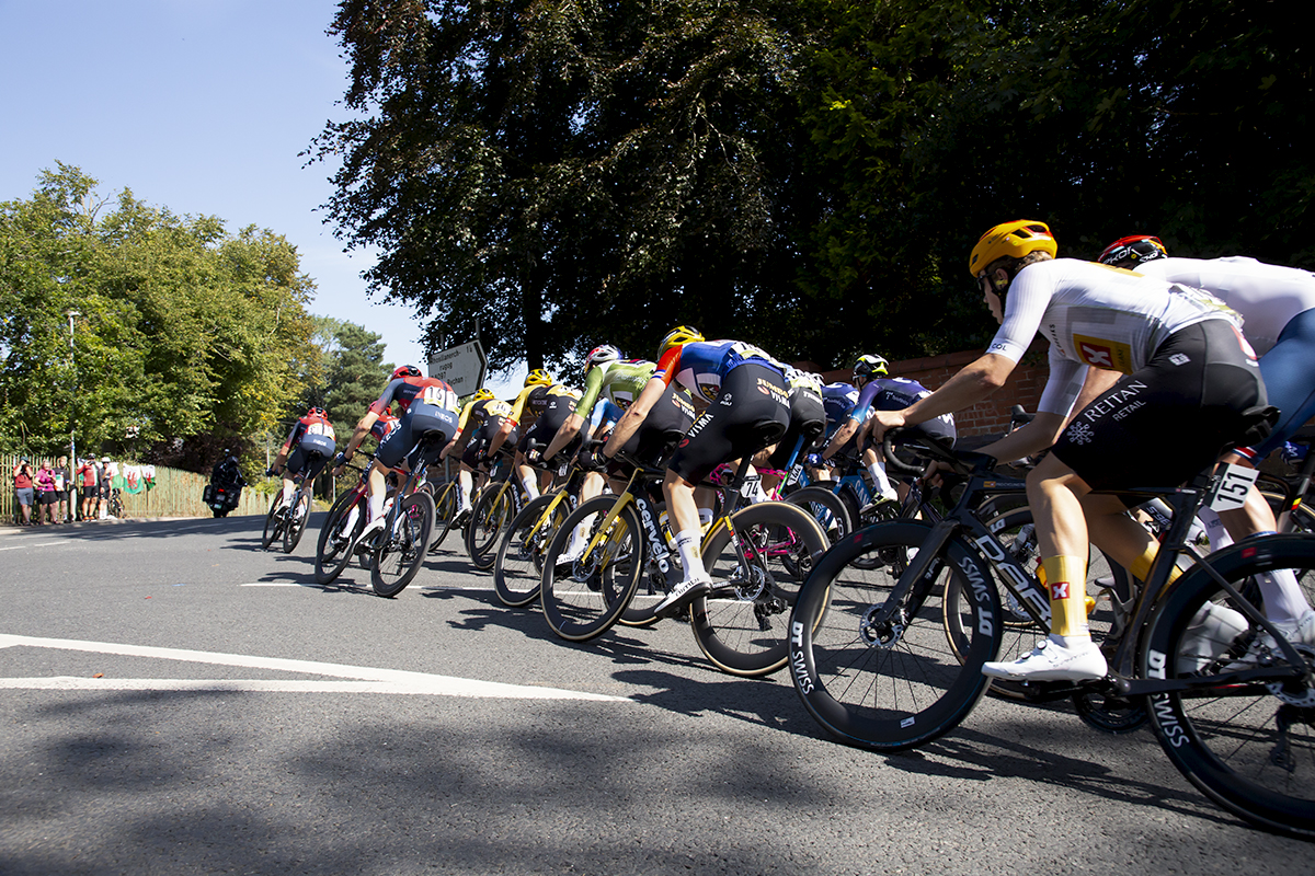 Tour of Britain 2023 - The peloton rounds a corner at speed