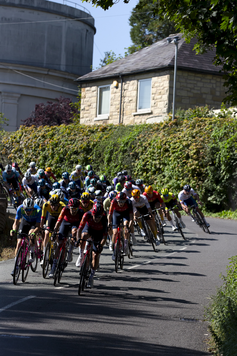 Tour of Britain 2023 -  The peloton descends a hill with the Legacy Tower in the background