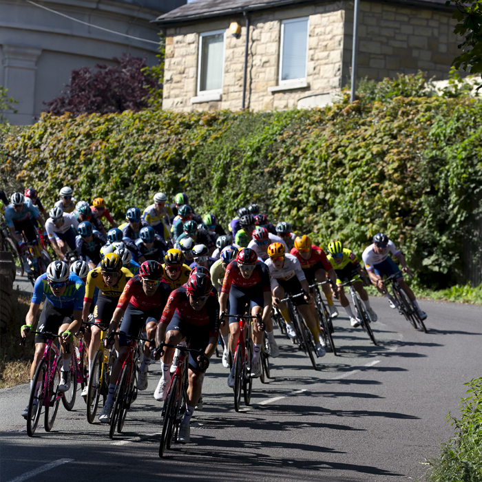 Tour of Britain 2023 -  The peloton descends a hill with the Legacy Tower in the background