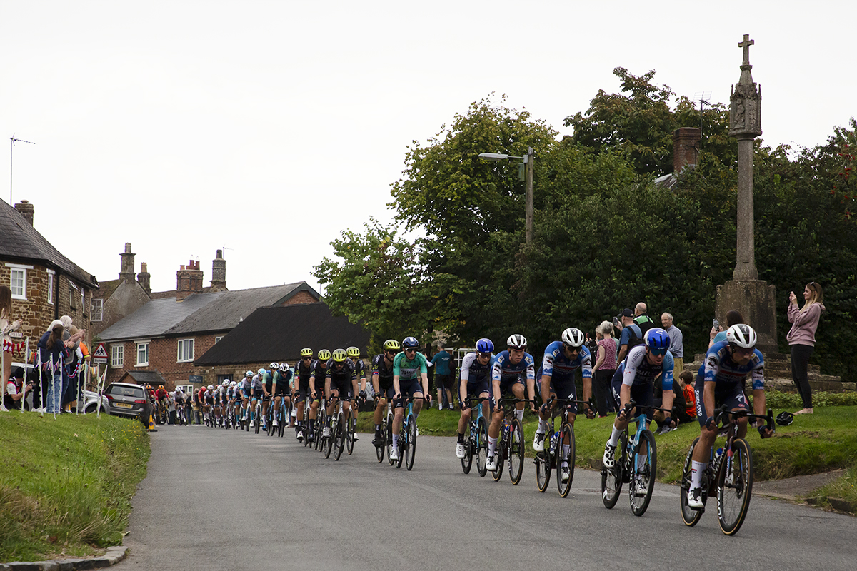 Tour of Britain 2024 - The peloton rides past the war memorial in Culworth on Stage 5